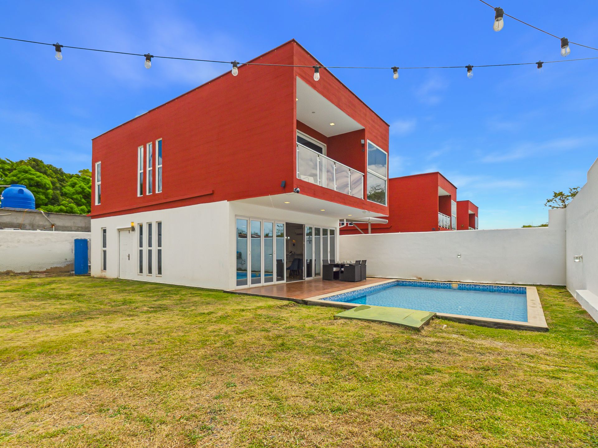 Fachada roja de Casa Roja Coronado, villa moderna de 2 pisos con jardín tropical